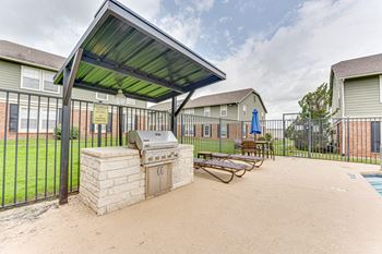 A covered patio area with a grill and seating area.